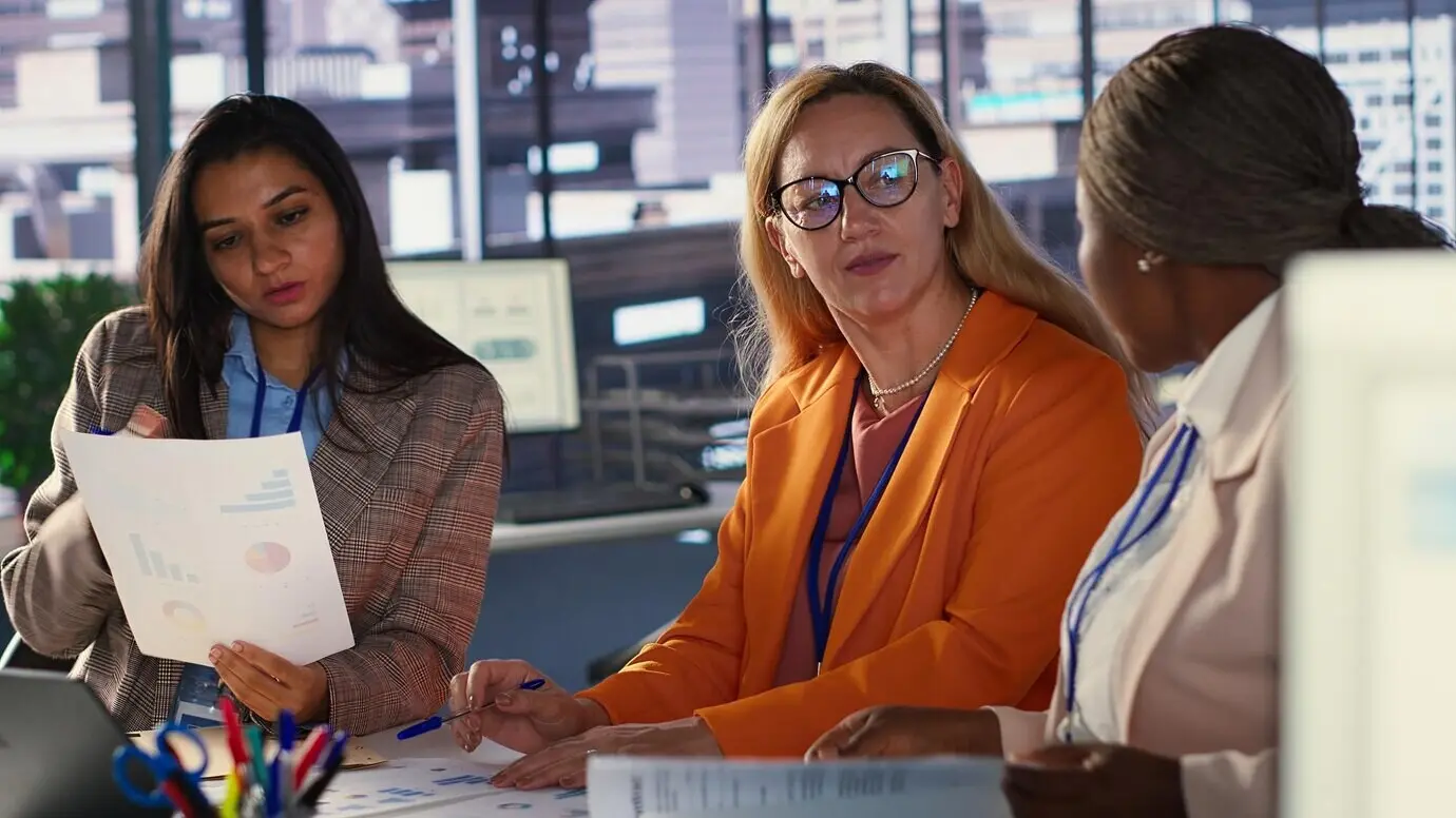 Mujeres ejecutivas ambiciosas colaboran en un entorno laboral diverso.