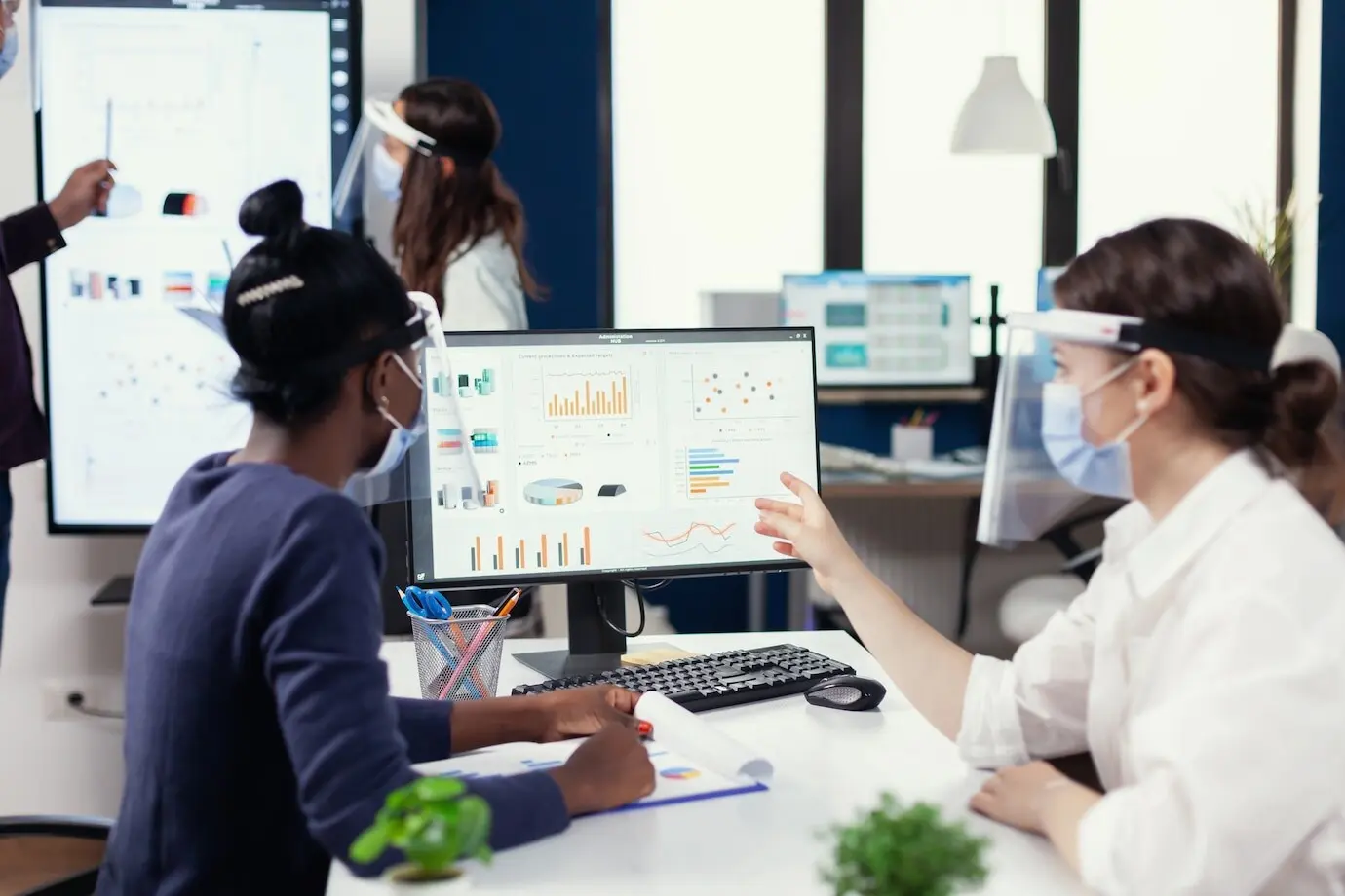 Gerente mostrando a un cliente africano el informe financiero anual, llevando mascarilla contra la COVID-19.