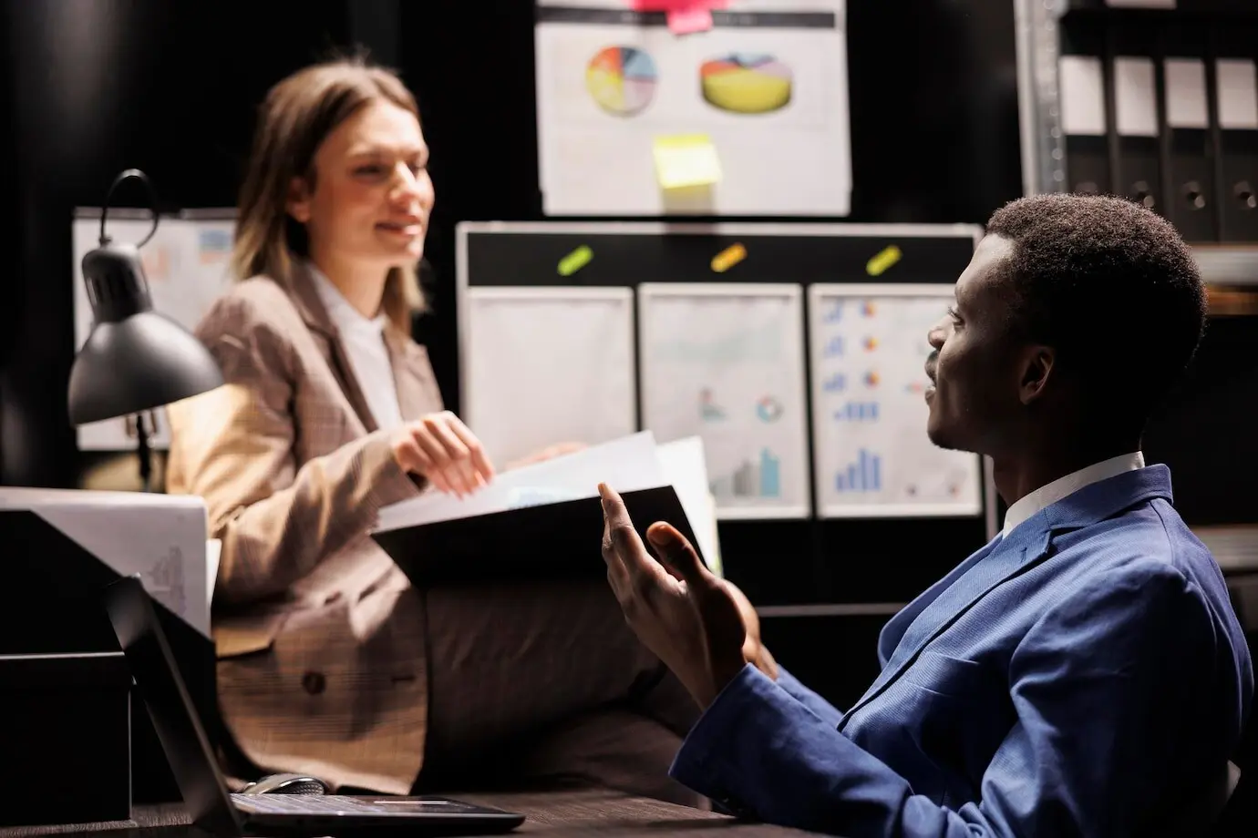 Empleados diversos del archivo analizan un registro burocrático, trabajando horas extra en un informe contable en la sala de archivo. Profesionales de negocios revisan documentos administrativos en el repositorio corporativo.